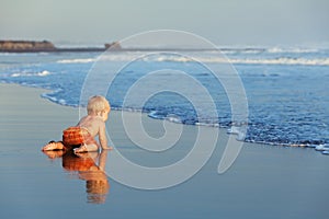 On sunset sand beach baby crawling to sea for swimming