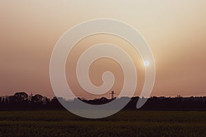 Sunset with sand suspended in the atmosphere, coluring the sky red, over some fields and hills photo