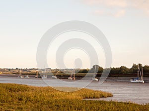 Sunset scene over river through country with moored boats and cl