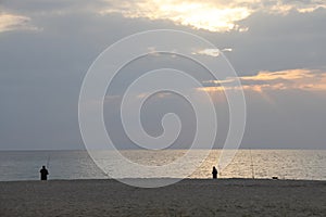 Sunset at sea, beach and fishermen silhouettes, minimalism, pacifying background