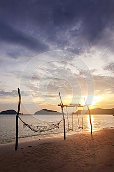Sunset sea beach travel island with rope hammock and wood swing landmark and twilight cloud sky background landscape in Koh Mak