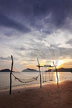 Sunset sea beach travel island with rope hammock and wood swing landmark and twilight cloud sky background landscape in Koh Mak