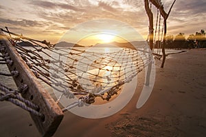 Sunset sea beach travel island with rope hammock and wood swing landmark and twilight cloud sky background landscape in Koh Mak