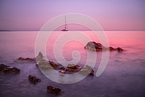 Sunset by the sea with boat and rocks at Palmanova, Mallorca, Spain