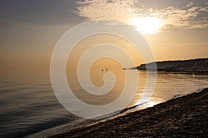 Sunset by the sea. The calm water of the sea. Fishermen in the distance at sea