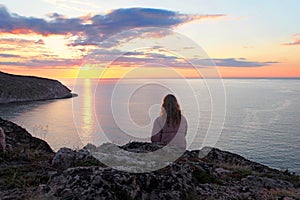 Sunset. Sea. Meditation on a coastal rock in a calm sea
