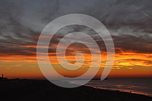 Sunset on sea with orange sky and dramatic clouds