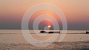 Sunset in the sea and silhouette of man hauling banana boat