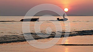 Sunset in the sea and silhouette of man hauling banana boat