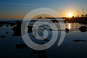 Sunset at the sea with stones and fishers