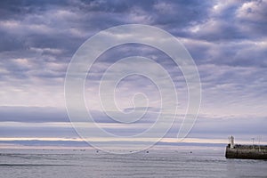 Sunset seascape at the lighthouse at the entrance to the harbor of Ribadesella, Asturias, Spain, with small leisure boats in the