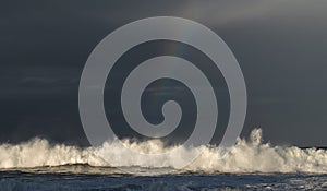 Sunset Seascape. Powerful ocean wave on the surface of the ocean. Wave breaks on a shallow bank. Stormy weather, stormy clouds sky