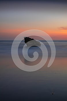 Sunset seascape. Rock in the ocean. Slow shutter speed. Soft focus. Silky water. Colorful sky. Amazing water reflection. Nature