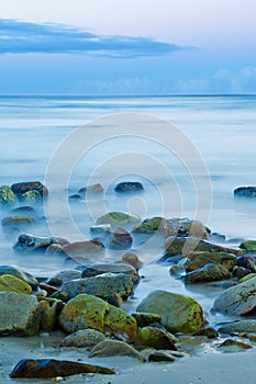 Sunset seascape with rocks in the foreground and smooth water