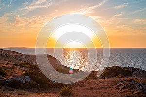 Sunset Seascape. Rocky seashore with yellow sun-scorched grass and a beautiful sky. Travel and tourism