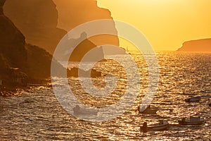 Sunset seascape with sea, colored sky with sun and volcanic cliffs, Akrotiri beach, Santorini, Greece, outdoor travel background