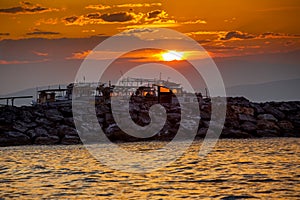 Sunset on the seashore. Moored fishing boats in the rays of the setting sun