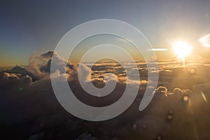 Sunset seen from an airplane with clouds in the foreground and in the distance