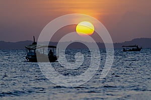 Sunset seen from Ribeira beach in Salvador, Bahia, Brazil. A boat sails at sea