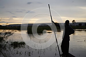 Sunset Shilouette Of An African Fisherman Standing In His Boat Holding A Push Pole photo