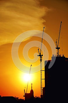 Sunset silhouette construction building tower crane cross on the roof of the church of the Sloane