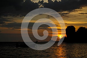 Sunset silhouette of fishing boat on sea beach in Thailand