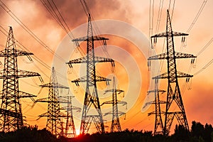 Sunset silhouette high voltage electric towers. Transmission lines on background of industry electricity towers.