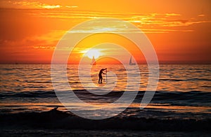 Sunset silhouette of paddle board on a sea. Relaxing on ocean. Sunrise over the sea and beautiful cloudscape. Colorful