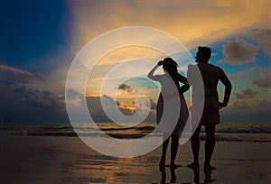 sunset silhouette of young couple in love hugging at beach