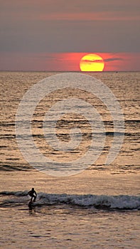 Sunset silhouetting a surfer