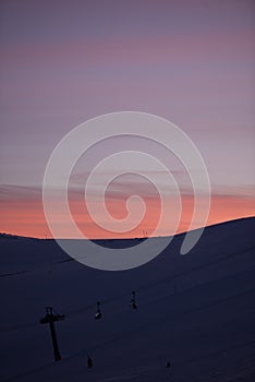 Sunset in skiing resort. Beautiful pink sky. Winter holiday in the mountains.