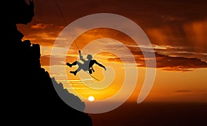 Sunset sky abseiling, mountain silhouette and hiking man hanging on shadow rope. Fitness risk, adventure freedom