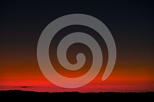 Sunset sky with bright red horizon and crescent moon photo