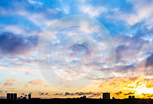 Sunset sky with clouds over urban houses in winter