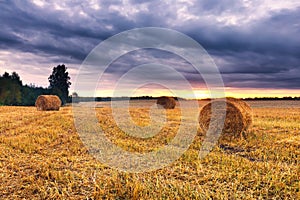 Sunset sky over field with straw bales