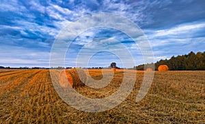 Sunset sky over field with straw bales