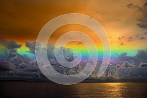 Sunset sky rainbow over silhouette orange cloud on the sea