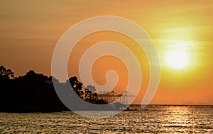 Sunset sky with silhouette of island and dock