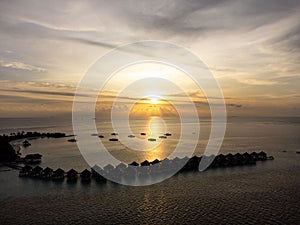 Sunset sky view reflecting on Maldives water with beach villas with horizon sunset