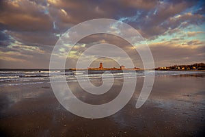 Sunset sky's reflection through the wet sand on the ocean beach and Penglai immortals pavilion, Yantai, Shandong, China