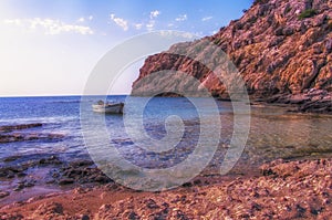 Sunset on a small boat and rocky headland