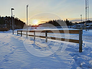 Sunset in a snowy day behind a fence in perspective