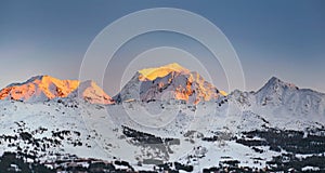 sunset on snowy mountain peak in alpine ski resort