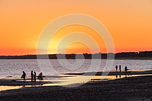 sunset on Solis beach, with some people still swimming in the sea photo