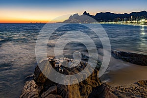 Sunset during the summer with city lights on at Ipanema beach