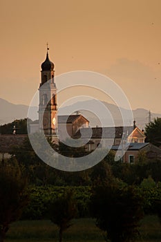 Sunset in summer with silhouette of church tower, Italy