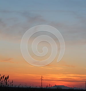 Sunset. The sun behind mountains. Scattered clouds and sky.