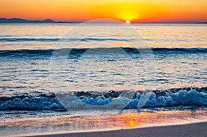 The sunset sun is going down behind the horizon. Tyrrhenian Sea bay with Elba island on the background at the sunset. Cala Violina