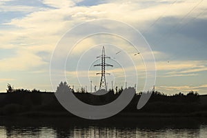 sunset. the sun is almost invisible. the power line passes through the lake. The birds are sitting on the wires.