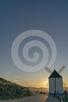 Sunset with the sun obscured by a windmill in the middle of the road, Consuegra, Castilla la Mancha. photo